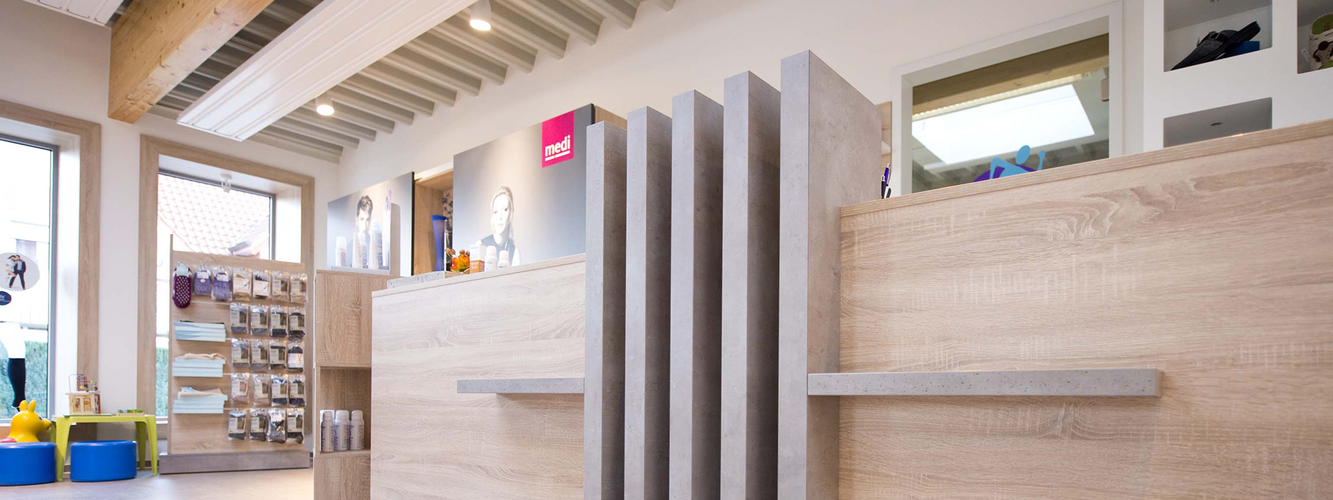 Innenansicht eines Ladens mit Holz-Empfangstresen und vertikalen Lamellen