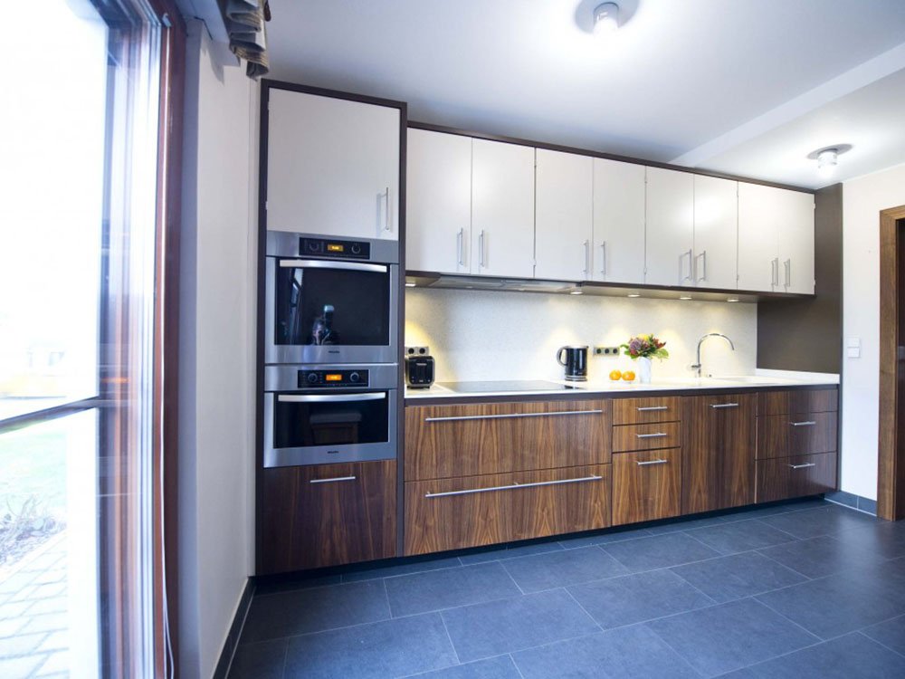 Moderne Einbauk&uuml;che mit Holzfronten, wei&szlig;en Oberschr&auml;nken und Einbauger&auml;ten